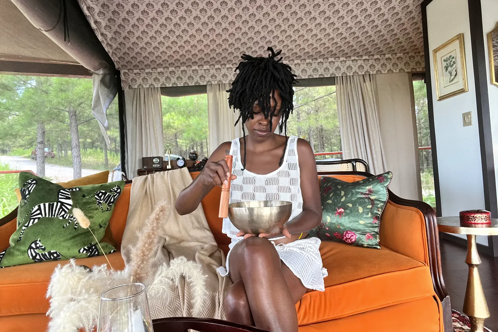 Lerae Funderburg seated in a calm, light-filled room holding a singing bowl.
